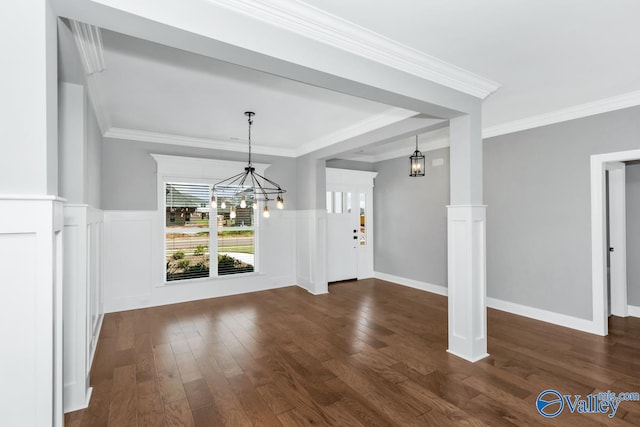 unfurnished dining area featuring crown molding, dark hardwood / wood-style flooring, ornate columns, and an inviting chandelier