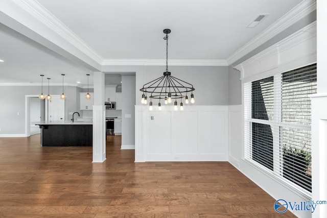 unfurnished dining area featuring crown molding, hardwood / wood-style floors, sink, and a notable chandelier