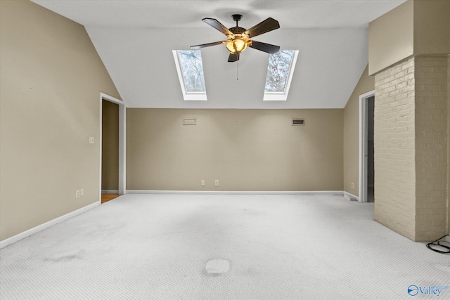 unfurnished living room with ceiling fan, vaulted ceiling with skylight, light colored carpet, and plenty of natural light