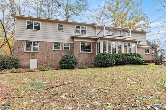 rear view of house featuring a sunroom, a balcony, and a yard