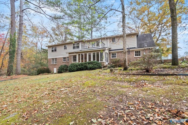 rear view of house featuring a yard and a balcony