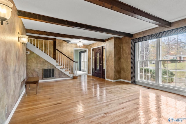 unfurnished living room with beam ceiling, a notable chandelier, and light wood-type flooring