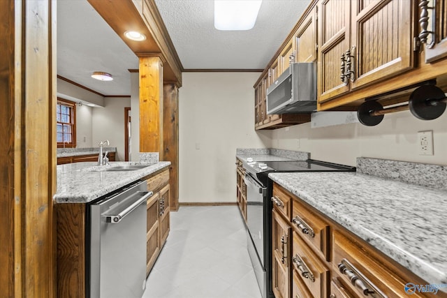 kitchen featuring sink, light stone counters, a textured ceiling, appliances with stainless steel finishes, and ornamental molding