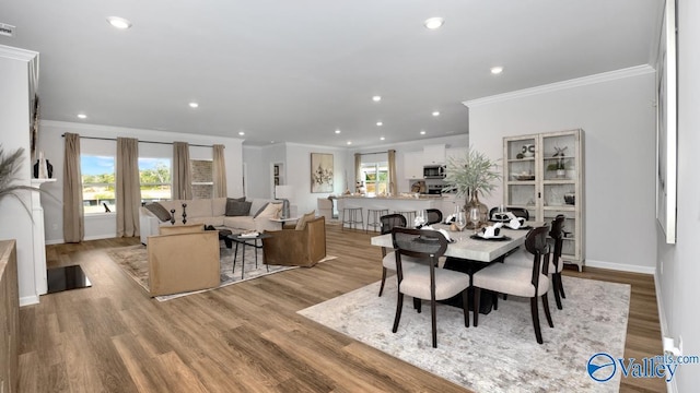 dining area featuring a healthy amount of sunlight, light hardwood / wood-style flooring, and ornamental molding