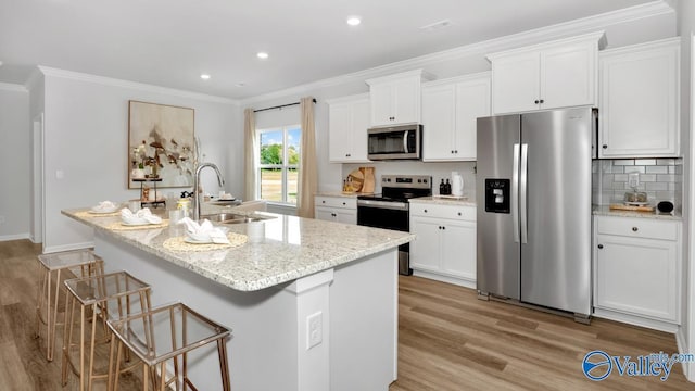 kitchen with appliances with stainless steel finishes, light stone counters, a kitchen island with sink, sink, and white cabinets