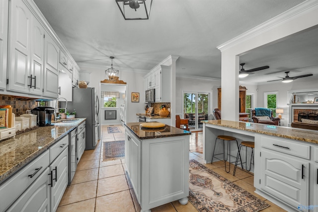 kitchen with ceiling fan with notable chandelier, a center island, crown molding, and decorative backsplash