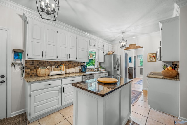 kitchen featuring white cabinets, decorative backsplash, appliances with stainless steel finishes, and a kitchen island