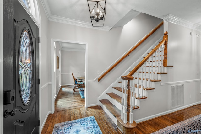 entrance foyer with hardwood / wood-style flooring, crown molding, and a chandelier