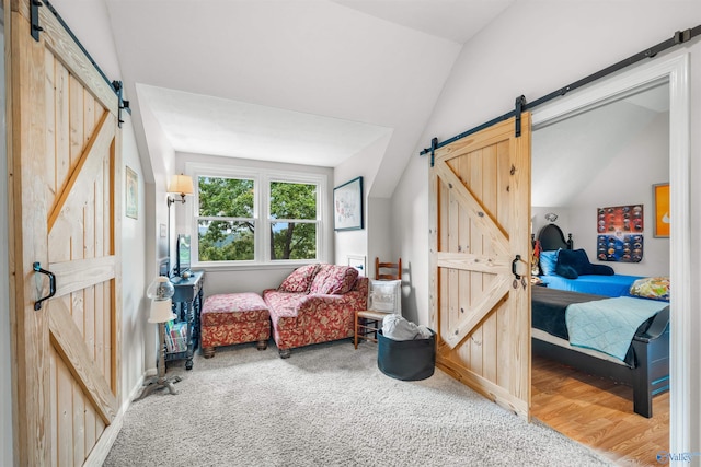 living area featuring vaulted ceiling, a barn door, and hardwood / wood-style floors