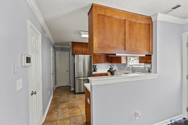 kitchen featuring a textured ceiling, visible vents, light countertops, ornamental molding, and freestanding refrigerator