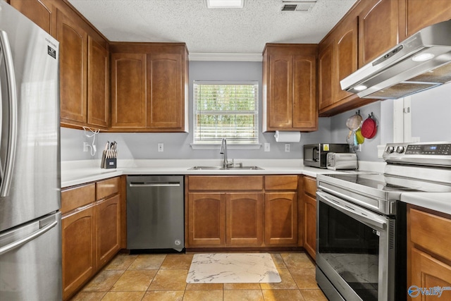 kitchen featuring under cabinet range hood, stainless steel appliances, a sink, light countertops, and brown cabinets