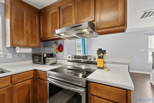 kitchen featuring under cabinet range hood, plenty of natural light, stainless steel electric range, and light countertops