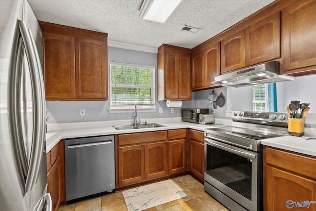 kitchen with a textured ceiling, under cabinet range hood, stainless steel appliances, a sink, and light countertops