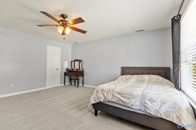 bedroom featuring baseboards, a textured ceiling, a ceiling fan, and light colored carpet