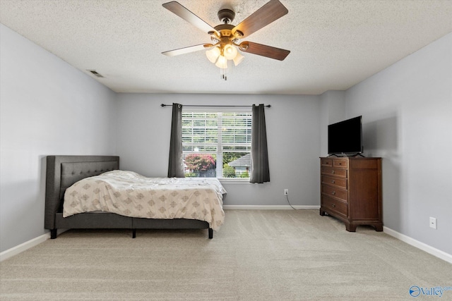 bedroom featuring visible vents, baseboards, light colored carpet, ceiling fan, and a textured ceiling