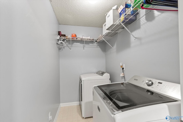 laundry room featuring laundry area, baseboards, a textured ceiling, washer and dryer, and light floors