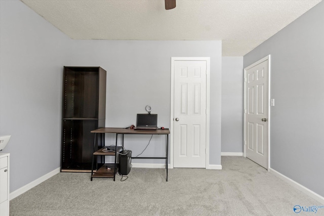 office featuring a ceiling fan, a textured ceiling, baseboards, and carpet flooring