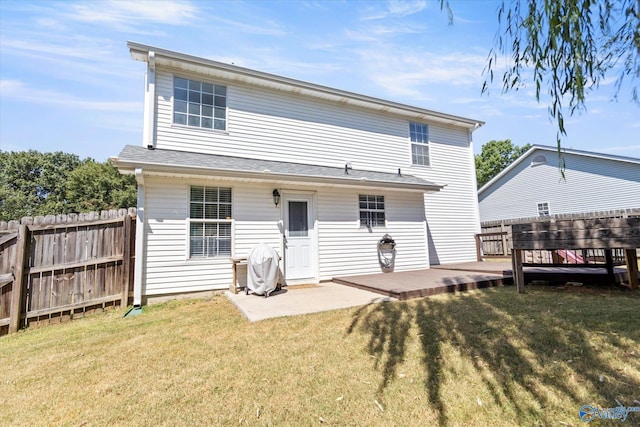 rear view of house with a lawn, a patio, a wooden deck, and fence