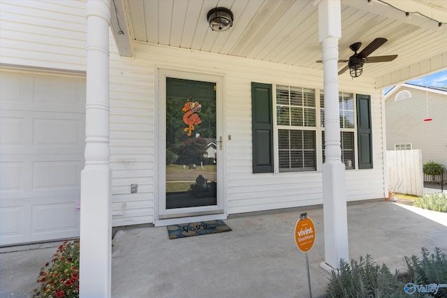 view of exterior entry featuring an attached garage, covered porch, and a ceiling fan