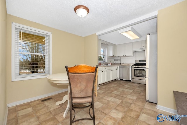 kitchen featuring white cabinetry, sink, stainless steel appliances, and a textured ceiling