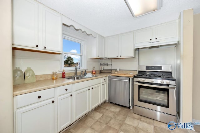 kitchen featuring appliances with stainless steel finishes, sink, a textured ceiling, and white cabinets