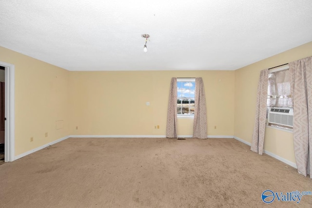 unfurnished room with cooling unit, light colored carpet, and a textured ceiling