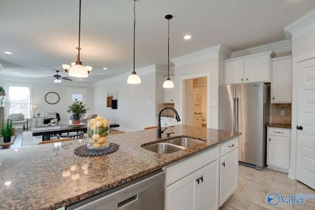 kitchen with backsplash, appliances with stainless steel finishes, white cabinets, a sink, and dark stone countertops