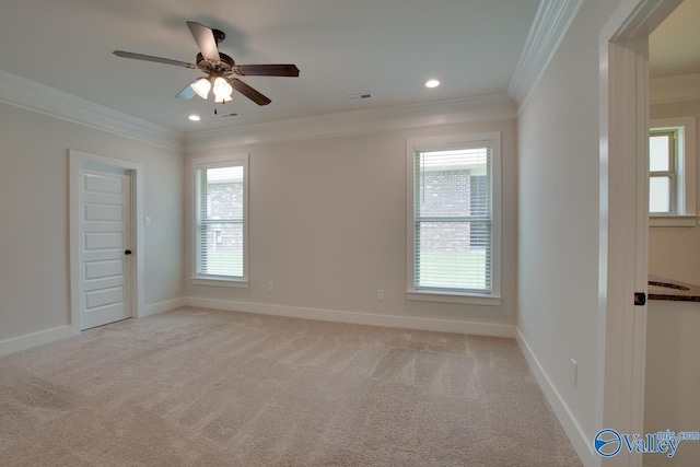 empty room featuring a wealth of natural light, light colored carpet, and crown molding