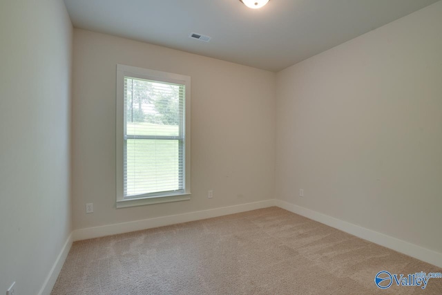 empty room with carpet, visible vents, and baseboards