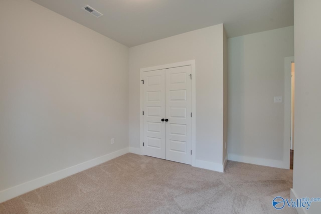 unfurnished bedroom featuring carpet, visible vents, baseboards, and a closet