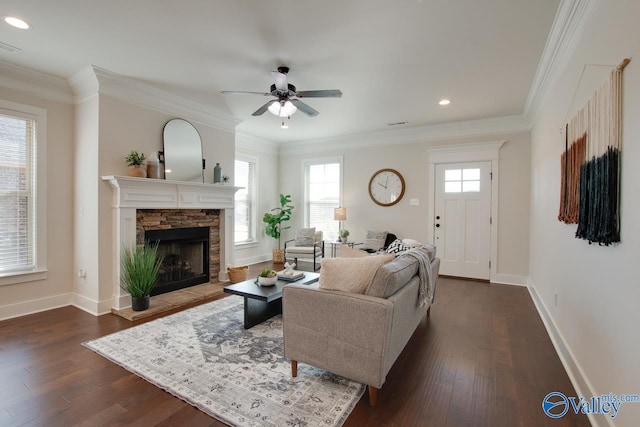 living area featuring ornamental molding, a stone fireplace, dark wood-type flooring, and baseboards