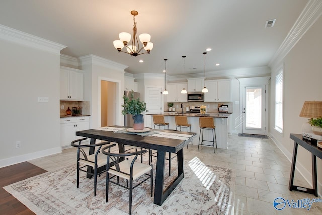 dining room with baseboards, an inviting chandelier, visible vents, and crown molding