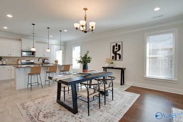 dining room with a chandelier, ornamental molding, visible vents, and baseboards