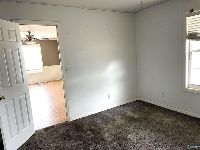 spare room featuring ceiling fan, dark wood-type flooring, and a healthy amount of sunlight