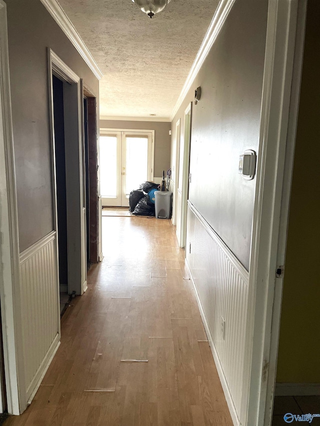 hallway with ornamental molding, light hardwood / wood-style floors, and a textured ceiling