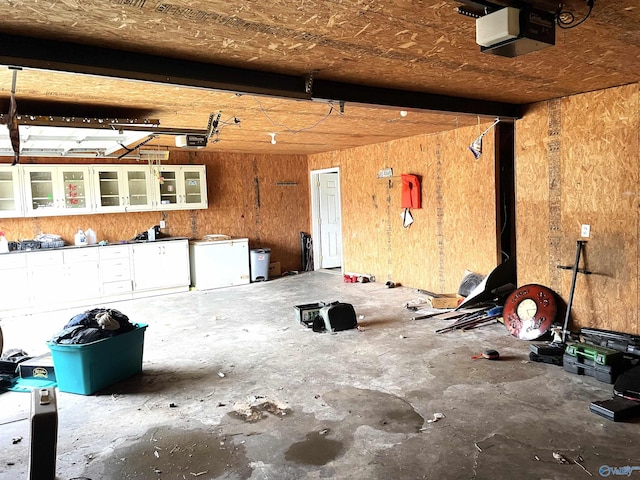 garage with a garage door opener, fridge, and wood walls