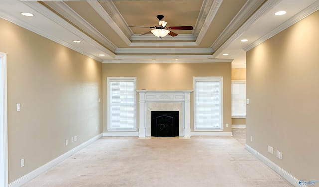 unfurnished living room with a tray ceiling, carpet, baseboards, and a premium fireplace