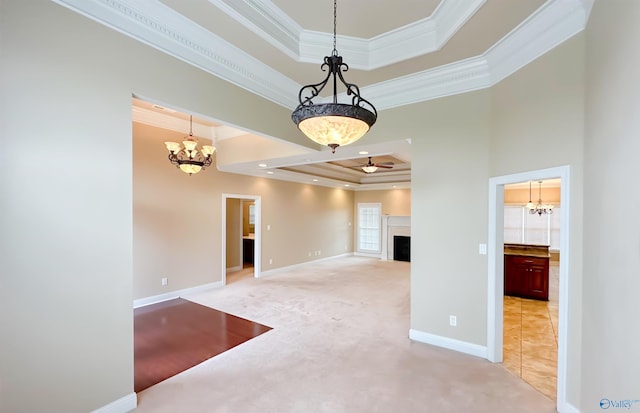 unfurnished room with light carpet, a fireplace, a tray ceiling, and ornamental molding