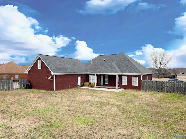 rear view of house with brick siding, a patio area, a yard, and fence