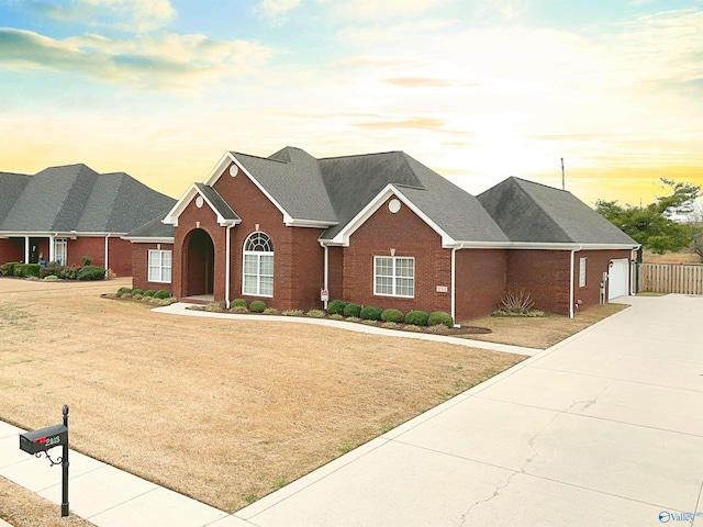 view of front of home with a garage, brick siding, concrete driveway, and a front yard