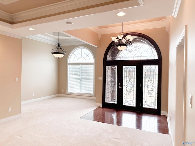 entrance foyer featuring baseboards, crown molding, an inviting chandelier, and carpet floors