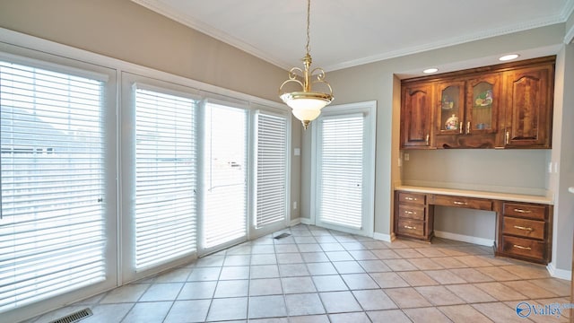 unfurnished dining area featuring light tile patterned floors, baseboards, crown molding, and built in desk