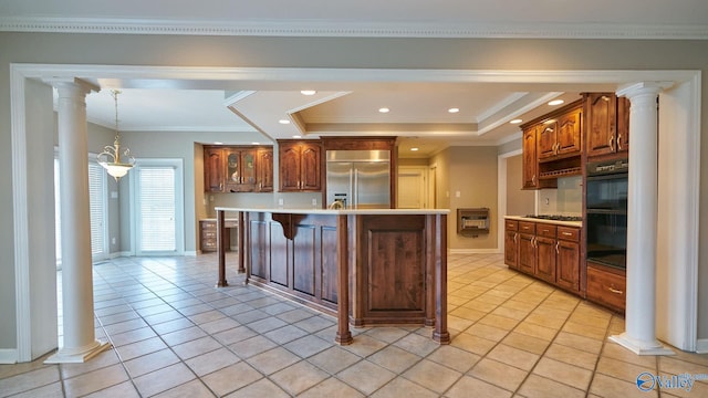 kitchen featuring appliances with stainless steel finishes, a kitchen island, crown molding, ornate columns, and a raised ceiling