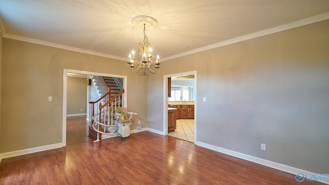 empty room featuring stairway, an inviting chandelier, ornamental molding, and light wood-style flooring