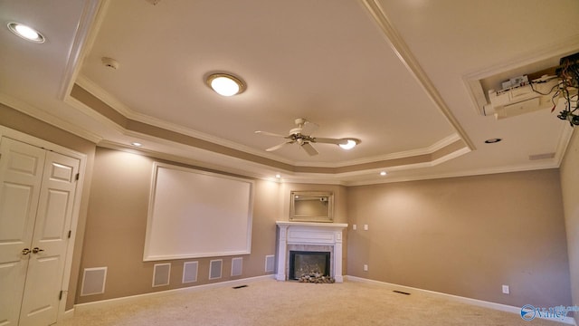 unfurnished living room featuring crown molding, ceiling fan, a tile fireplace, a raised ceiling, and carpet flooring
