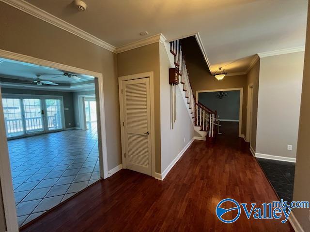 corridor with baseboards, crown molding, wood finished floors, and stairs