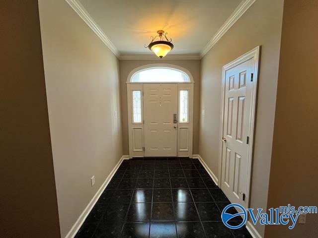 foyer entrance featuring dark tile patterned flooring and ornamental molding