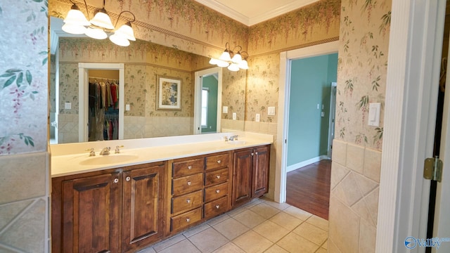 full bath featuring tile patterned floors, a sink, an inviting chandelier, wallpapered walls, and crown molding