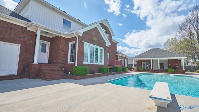 view of pool with a patio and a diving board