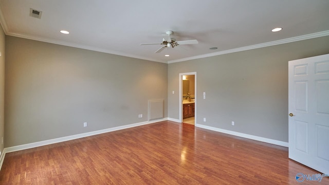 spare room featuring wood finished floors, ceiling fan, baseboards, ornamental molding, and visible vents